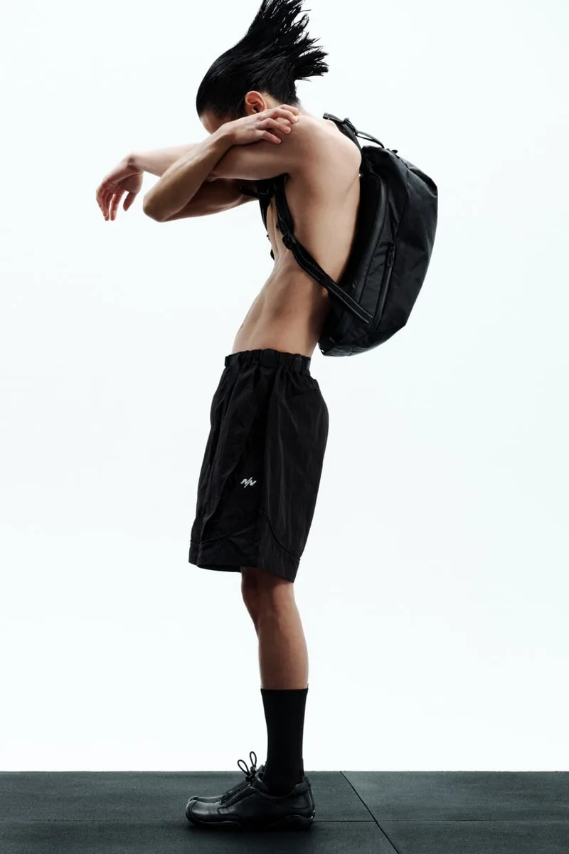Personne debout avec sac à dos et short noir en mouvement.