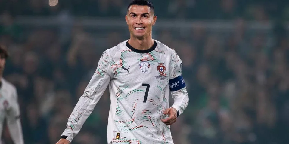 Footballeur souriant en maillot blanc avec brassard de capitaine.