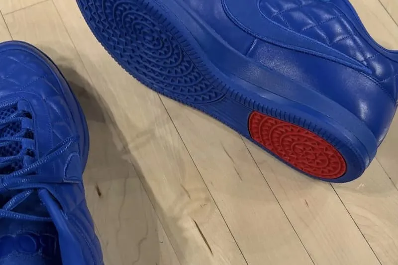 Chaussures bleues sur un sol en bois avec semelle rouge visible.