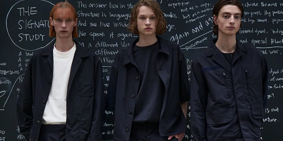 Trois mannequins posant devant un tableau noir avec des écritures blanches.