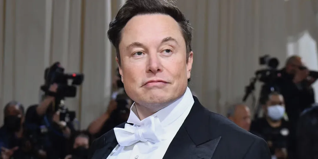 Homme en smoking au gala avec des photographes en arrière-plan.