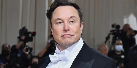 Homme en smoking au gala avec des photographes en arrière-plan.