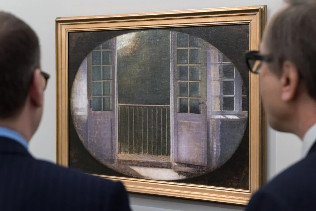 Deux hommes regardant une peinture abstraite dans un cadre doré.