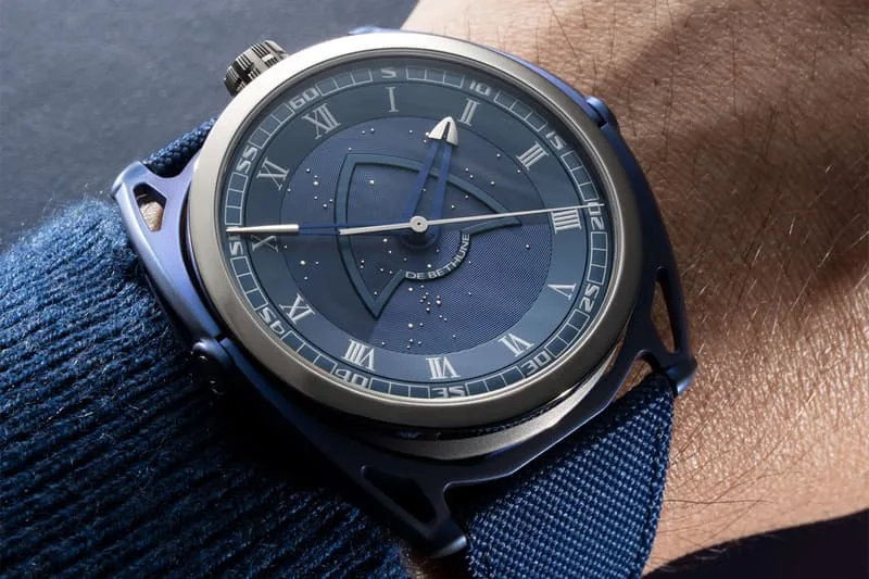 Montre bleue avec chiffres romains et motifs étoilés, bracelet en tissu bleu.