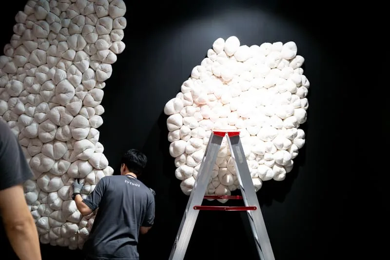 Un homme travaille sur une installation d'art blanc avec une échelle.
