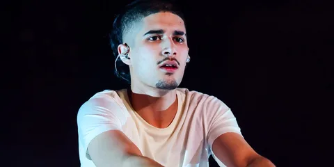 Un homme en t-shirt blanc performe sur scène.