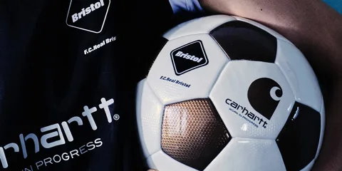 Ballon de football avec logos Bristol et Carhartt F.C. sur un fond noir.