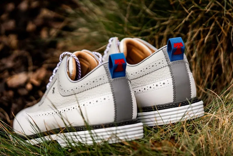 Chaussures blanches avec détails gris et étiquettes rouges et bleues.