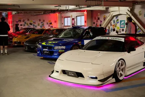 Voitures de sport exposées dans un parking éclairé rouge.