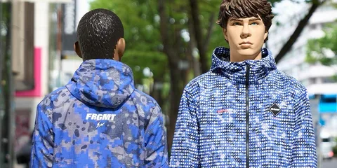 Deux mannequins portant des vestes bleues à motifs sur un fond urbain.