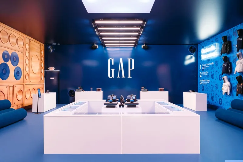 Magasin Gap moderne avec présentoirs et éclairage bleu.
