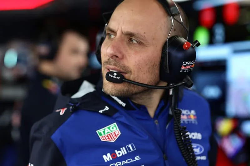 Homme avec casque et vêtements Red Bull dans un garage de course.