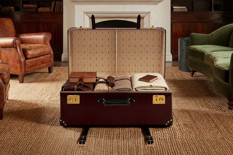 Valise ouverte en cuir avec vêtements et carnets dans un salon élégant.
