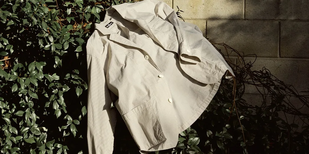 Veste beige suspendue sur des branches et des feuilles.