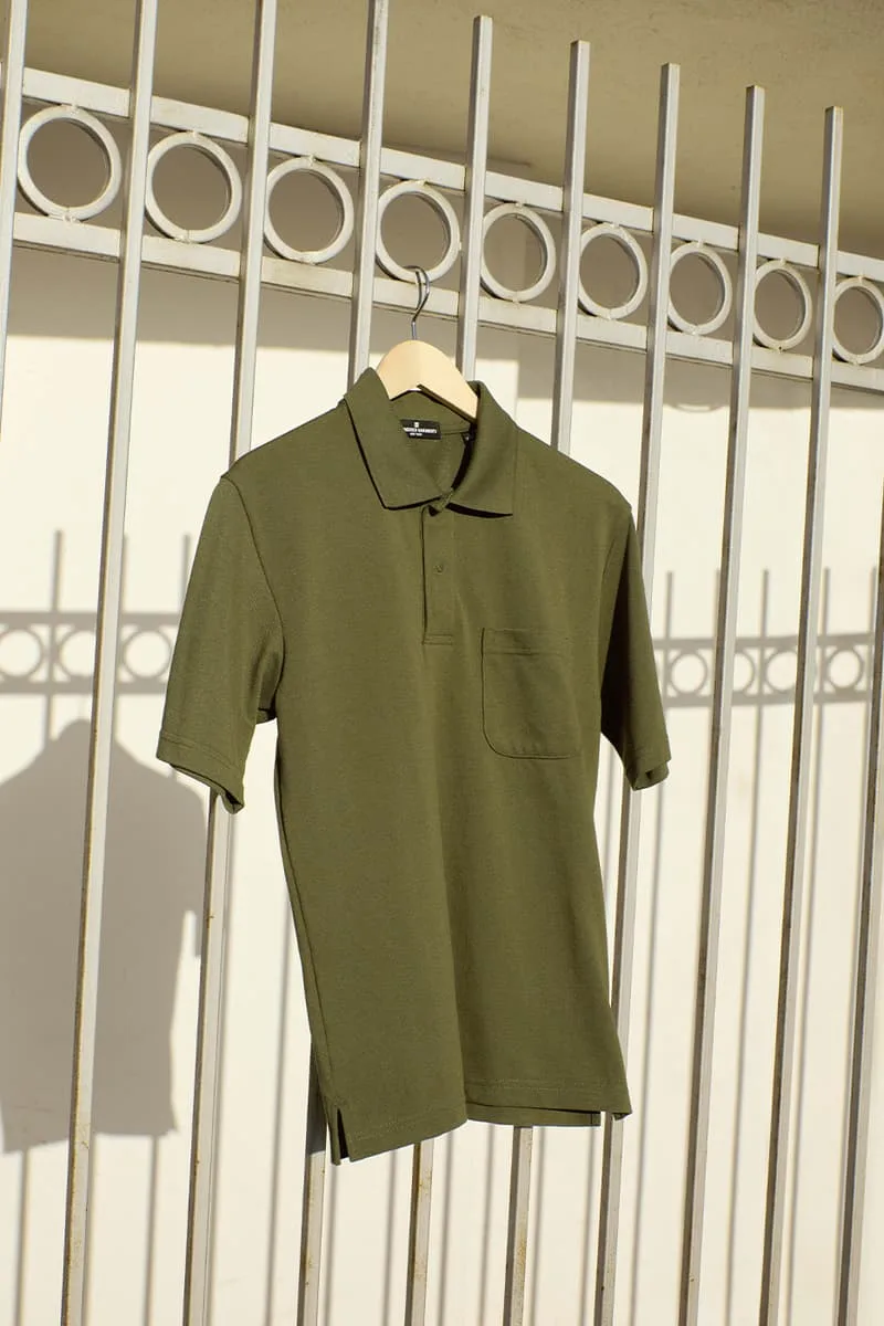 Polo vert suspendu à un portemanteau sur une grille.