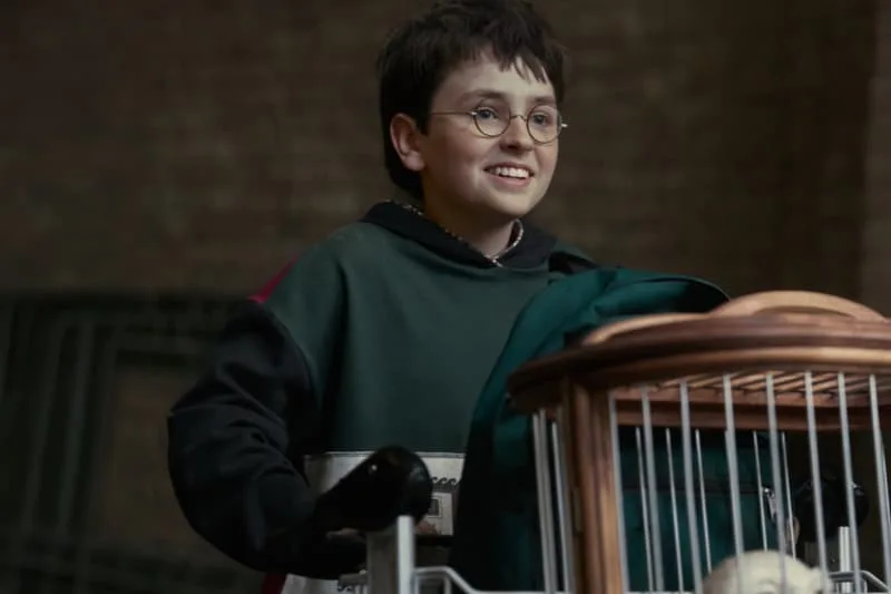 Garçon souriant avec lunettes et cage à oiseaux