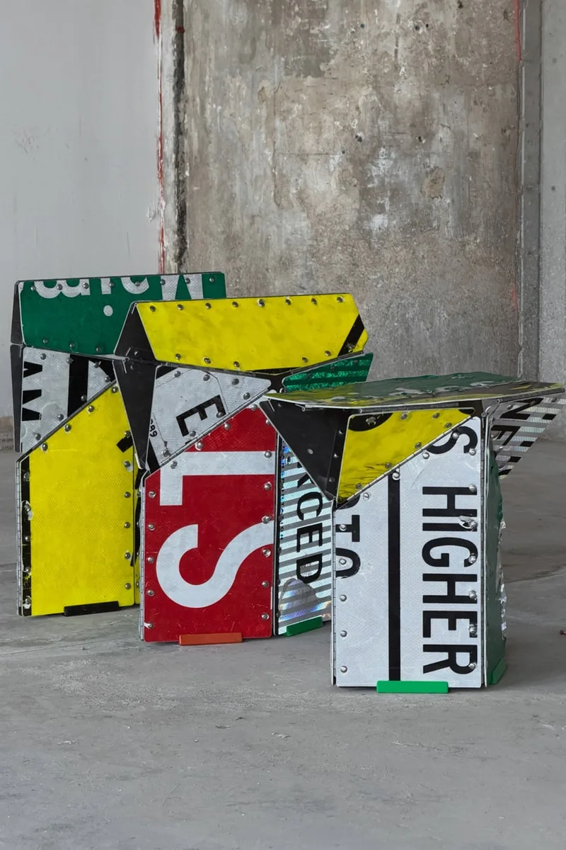 Tabourets faits de panneaux de signalisation recyclés, couleurs vives et texture industrielle.