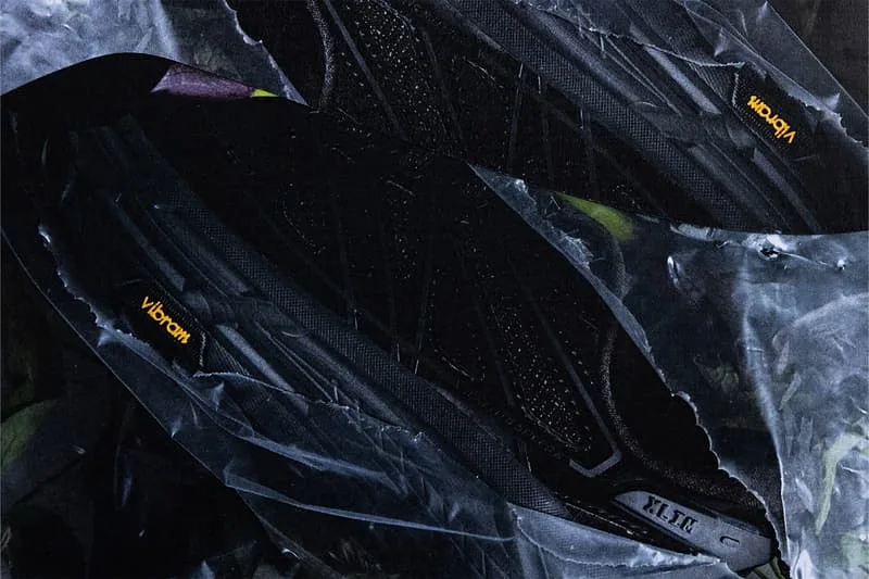 Deux chaussures noires avec détails Vibram sur fond texturé.