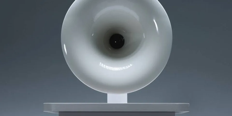 Sculpture circulaire blanche sur socle, arrière-plan gris