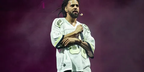 Personne chante sur scène avec micro et tenue de scène blanche.