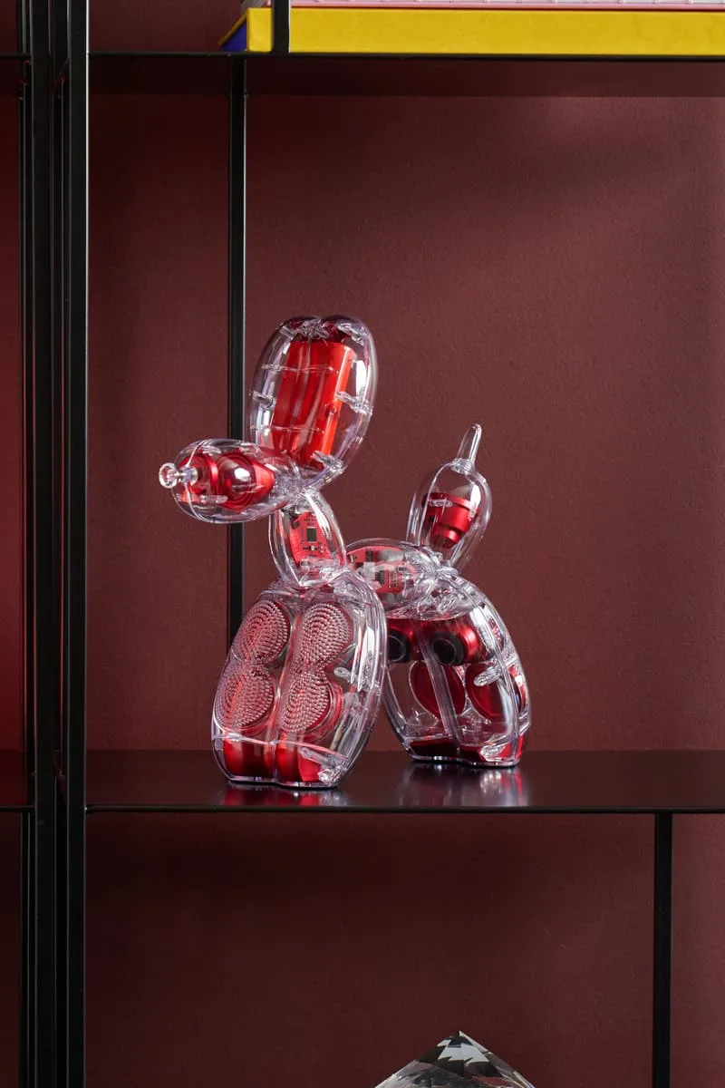 Sculpture chien ballon transparent avec détails rouges.