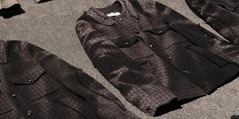 Manteaux texturés marron sur sol gris, avec poches et boutons.