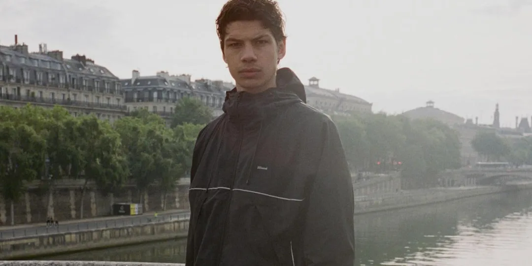 Homme en veste noire debout sur un pont à Paris.