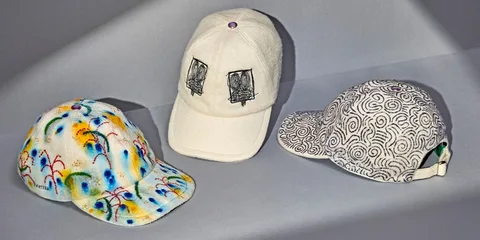 Trois casquettes artistiques colorées sur fond gris.