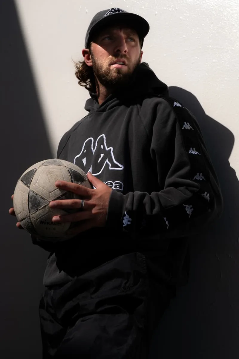 Homme en hoodie noir tenant un ballon de football