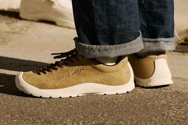 Chaussures beige avec lacets rouges et jeans.