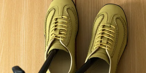 Chaussures jaunes avec lacets sur un sol en bois.