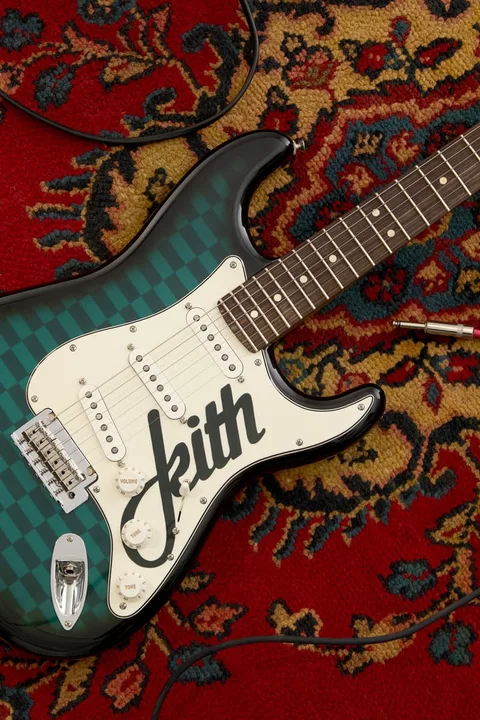 Guitare électrique verte Kith sur un tapis rouge.