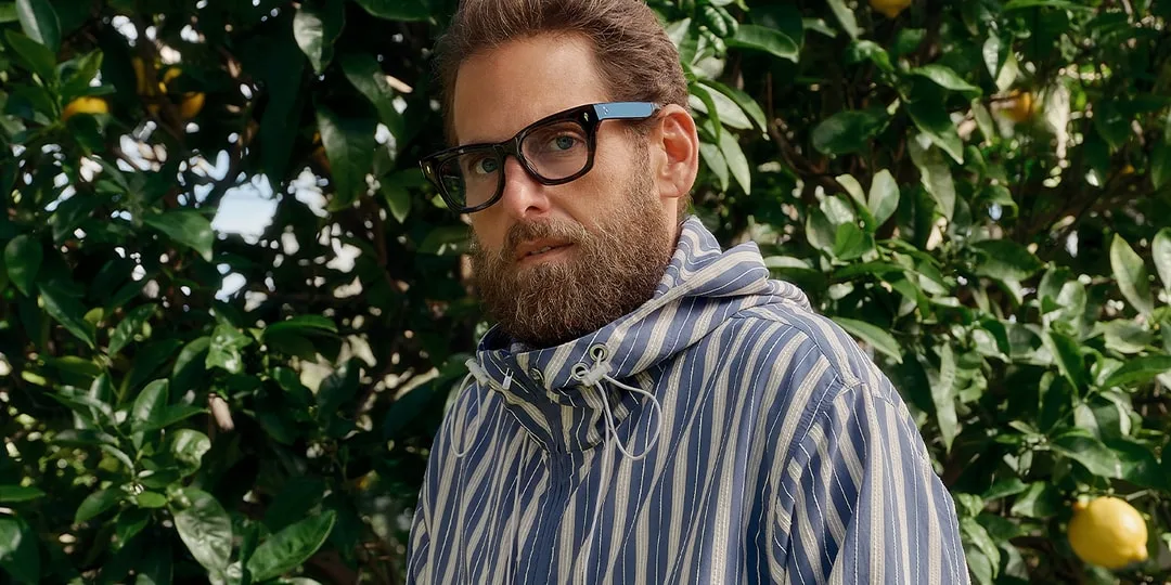 Homme barbu avec des lunettes devant des arbres.