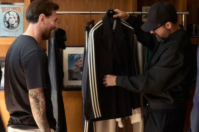 Deux hommes regardant un costume noir avec des rayures blanches.