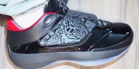 Chaussure noire avec motifs gris et détails rouges.
