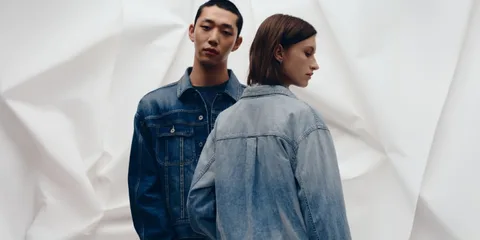 Deux personnes posant en vestes en jean, fond blanc plissé.