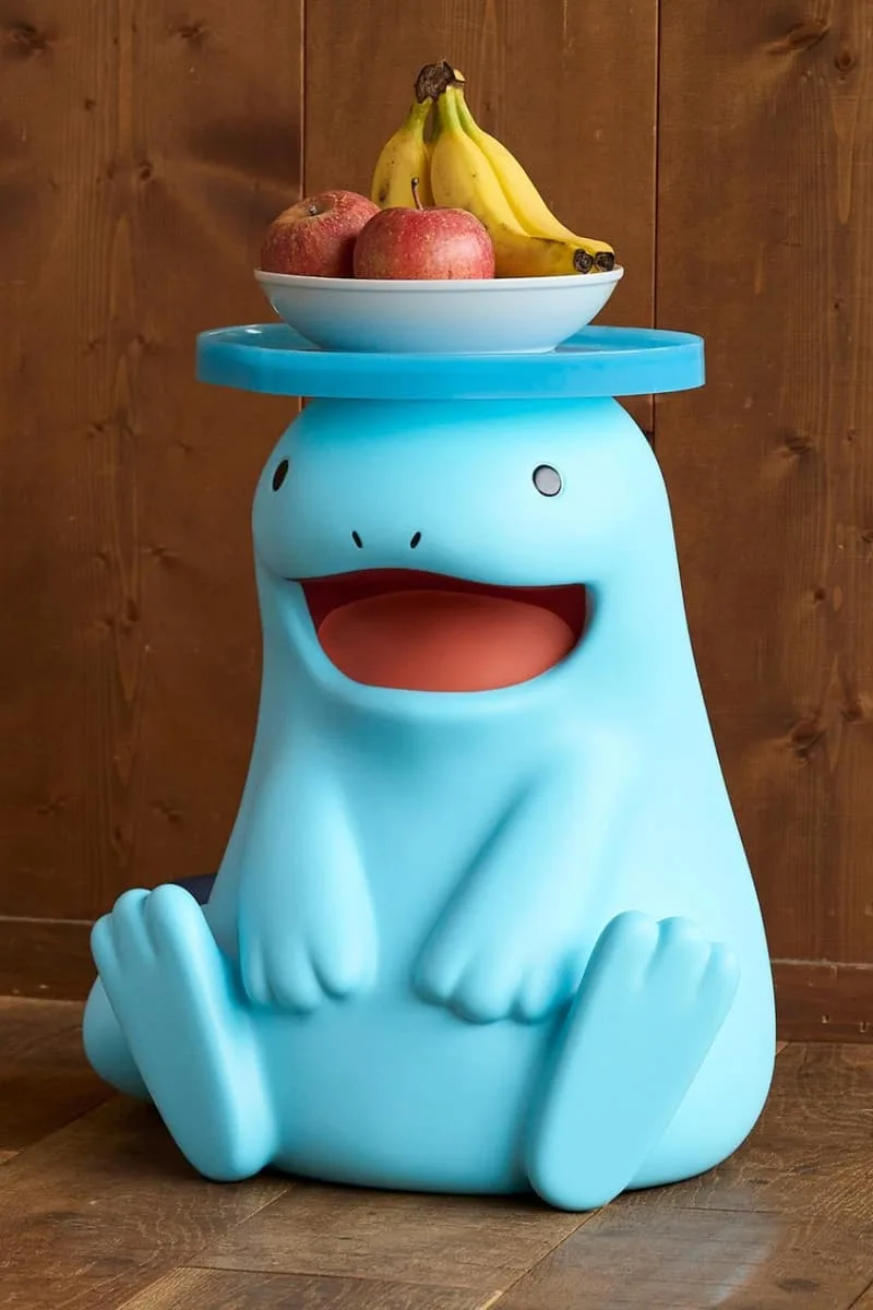 Tabouret bleu ludique avec bol de fruits dessus, contre un mur en bois.