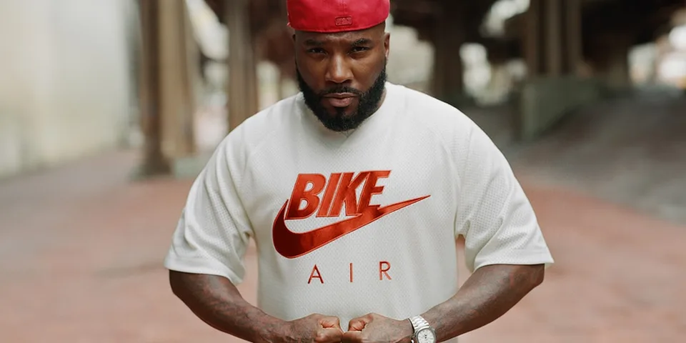 Homme avec t-shirt blanc et casquette rouge dans une rue urbaine.