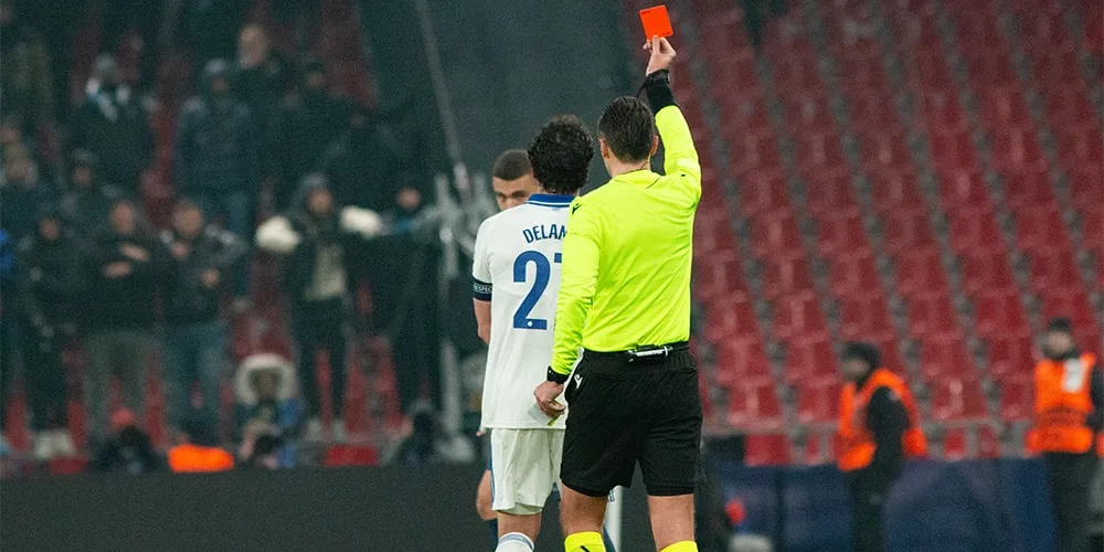 Arbitre montre un carton rouge à un joueur de football sur le terrain.
