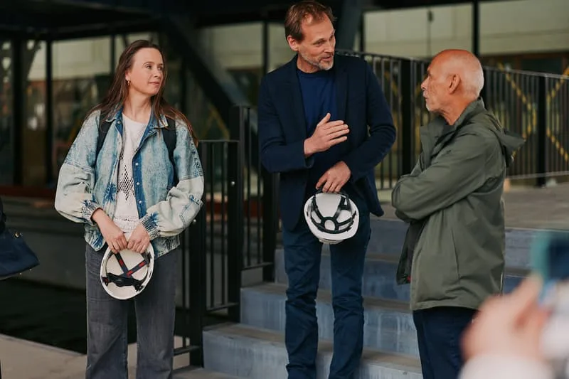Trois personnes discutant avec des casques dans les mains.