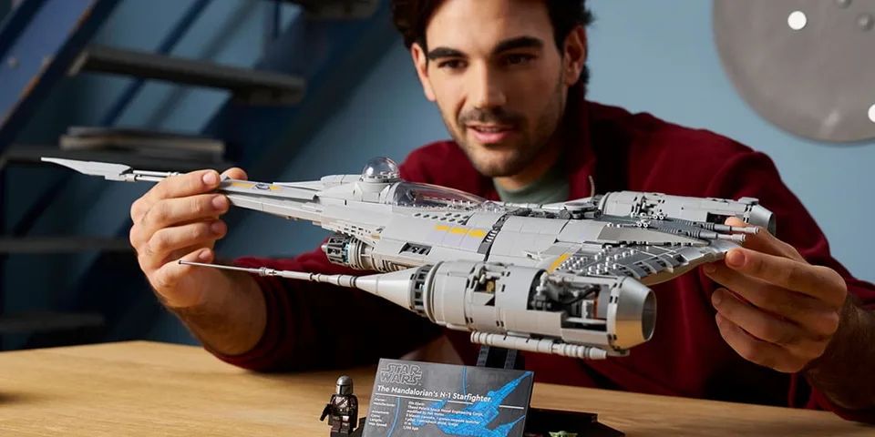 Homme construisant un vaisseau spatial Lego Star Wars sur une table.