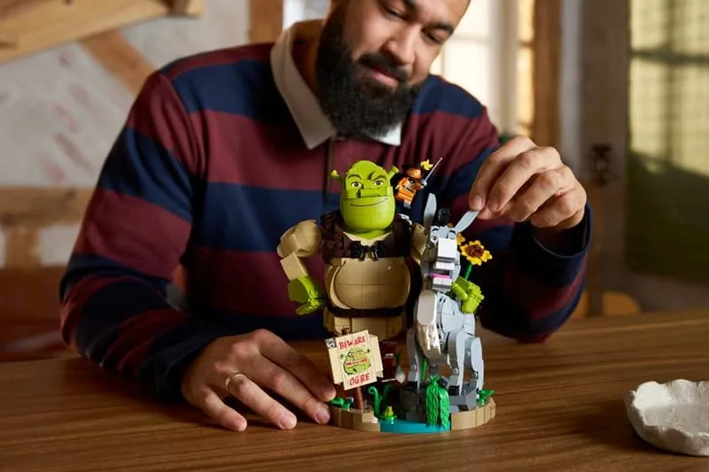 Homme construisant un ensemble LEGO de Shrek et âne à une table