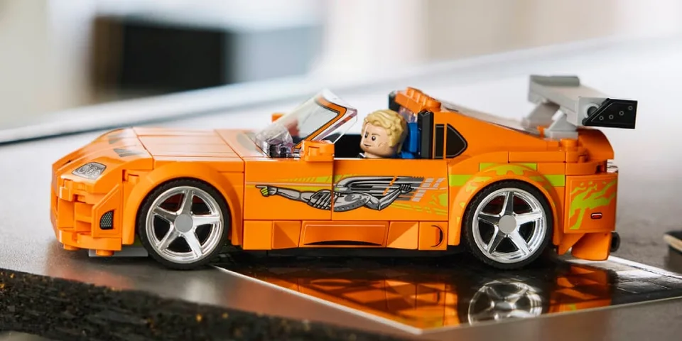Voiture de course en jouet orange avec personnage Lego à l'intérieur.