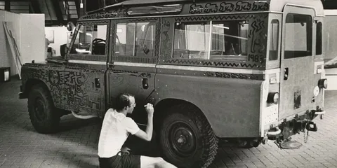 Artiste peignant un véhicule vintage avec des motifs abstraits.
