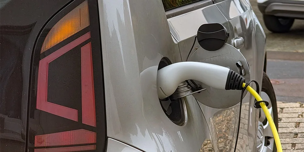 Voiture électrique grise en cours de chargement avec câble jaune