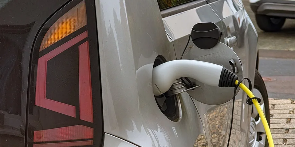 Voiture électrique grise en cours de chargement avec câble jaune