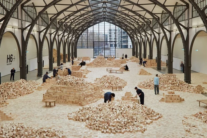 Installation artistique avec des blocs de bois dans une grande salle.