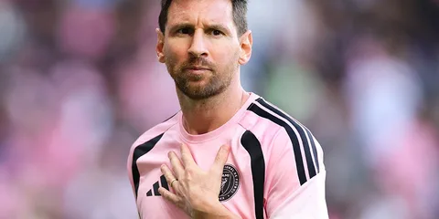 Joueur de football en tenue rose et noire, main sur le cœur.