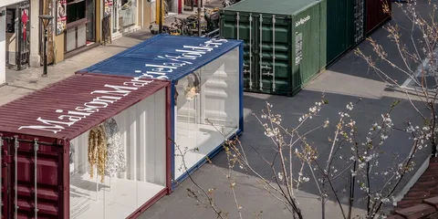 Conteneurs colorés transformés en vitrines sur une place.
