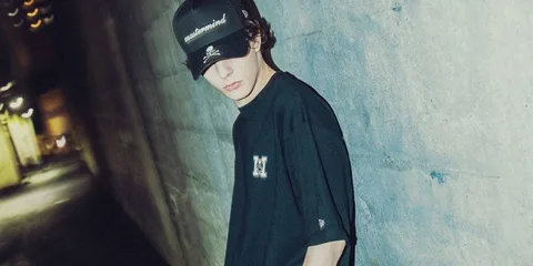 Jeune homme avec casquette sombre dans une ruelle éclairée.